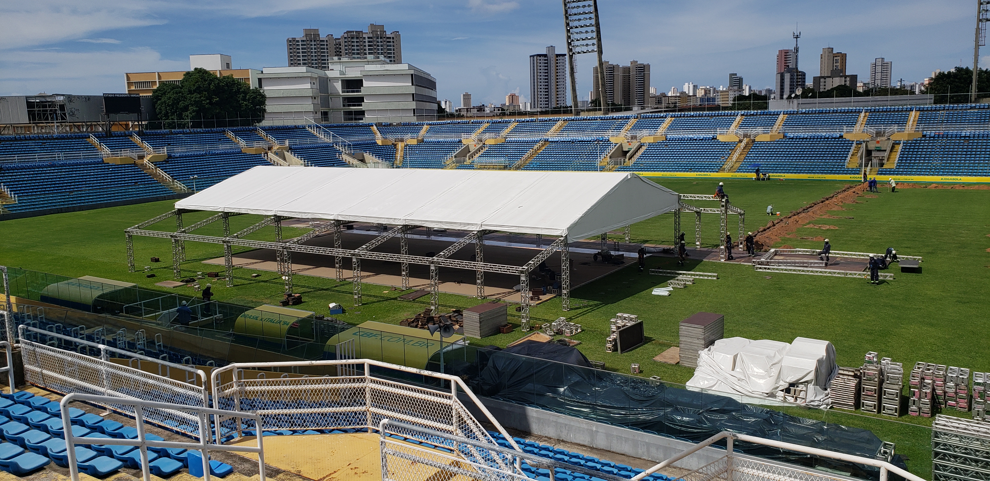 tenda branca e operários trabalhando em estádio de futebol